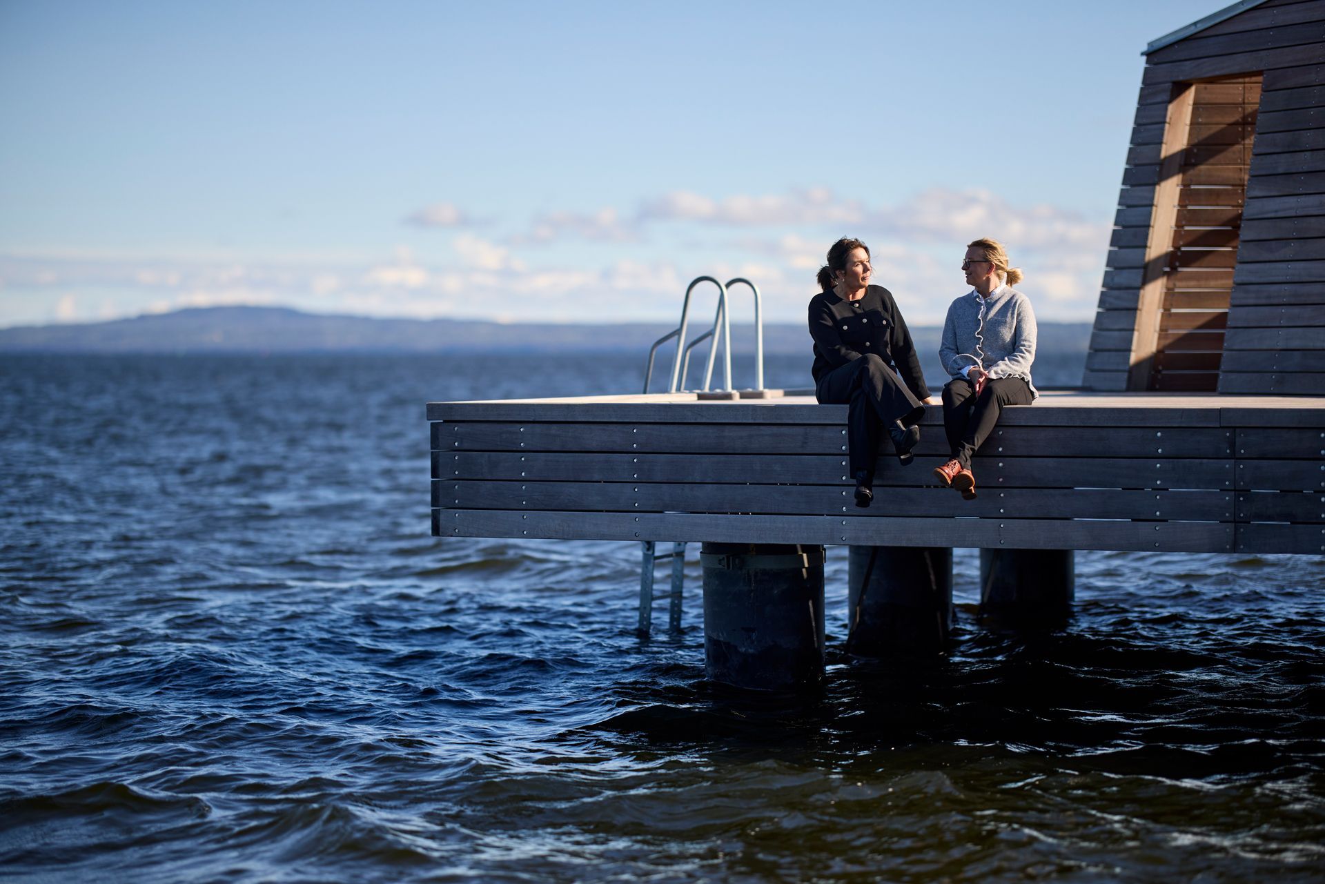 Malin och Linda p&aring; V&auml;nerh&auml;lsan sitter p&aring; bryggan vid Framn&auml;s Strandpark.