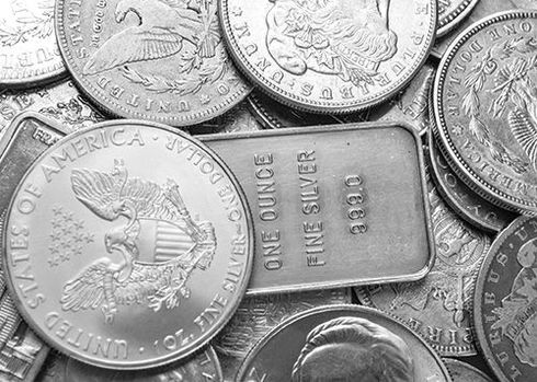 A pile of silver coins and a bar of fine silver