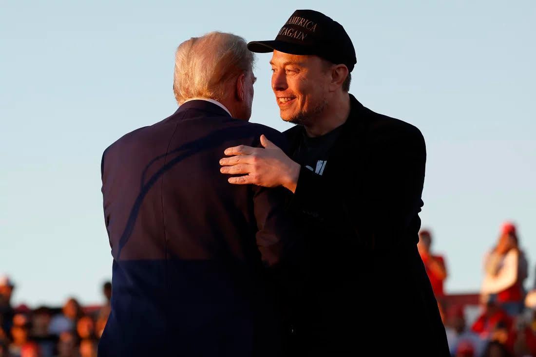 A man in a hat is hugging another man in a suit.