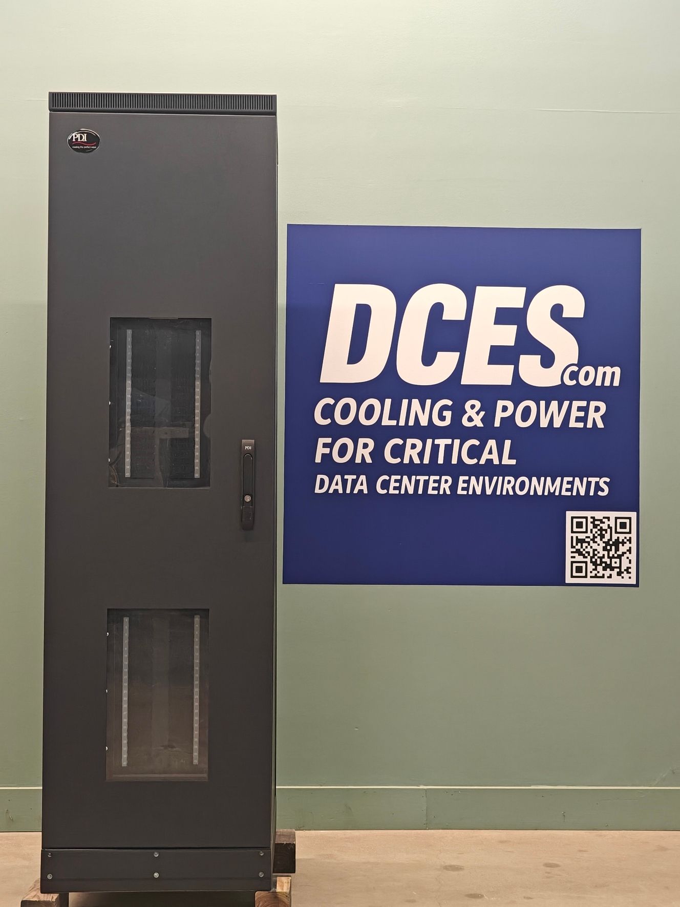 Dark server rack next to a blue sign for DCES, cooling and power solutions.