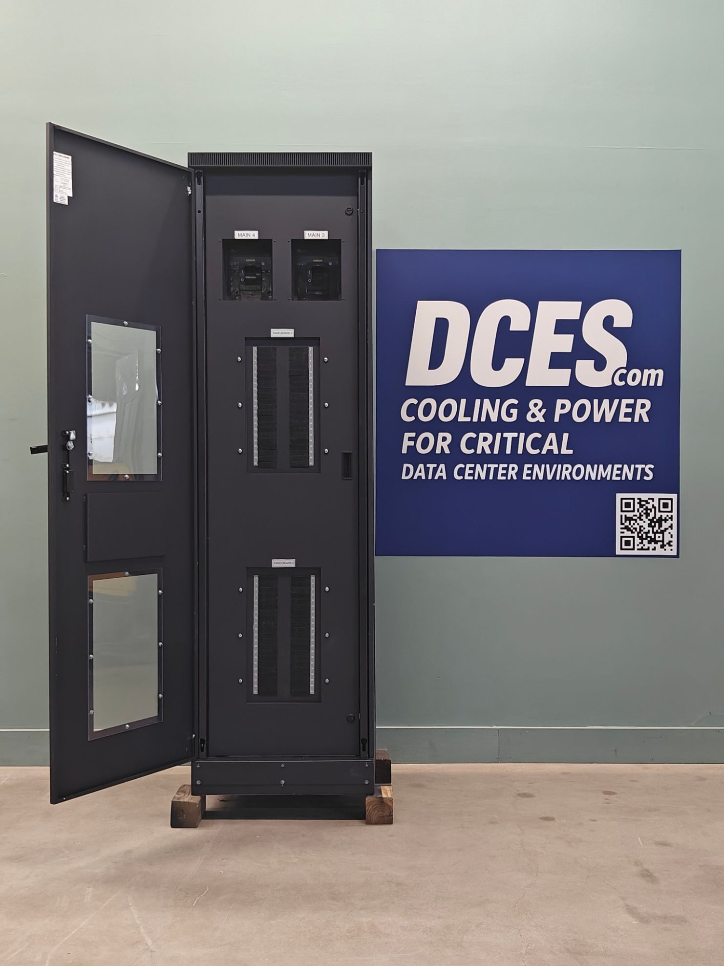Black data center cabinet with open door; DCES sign in background.