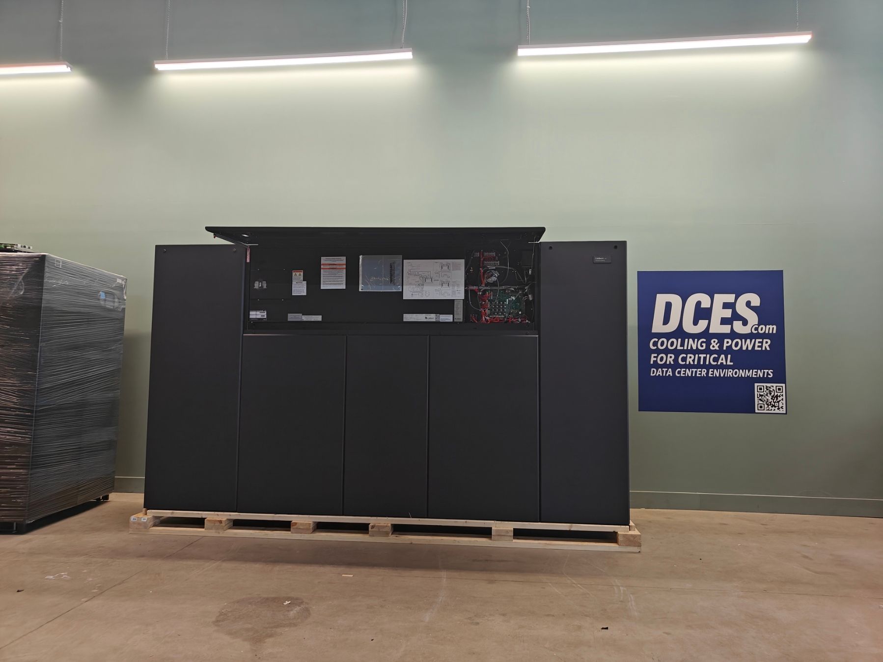 Large, dark machinery unit on a pallet inside a building, with a 