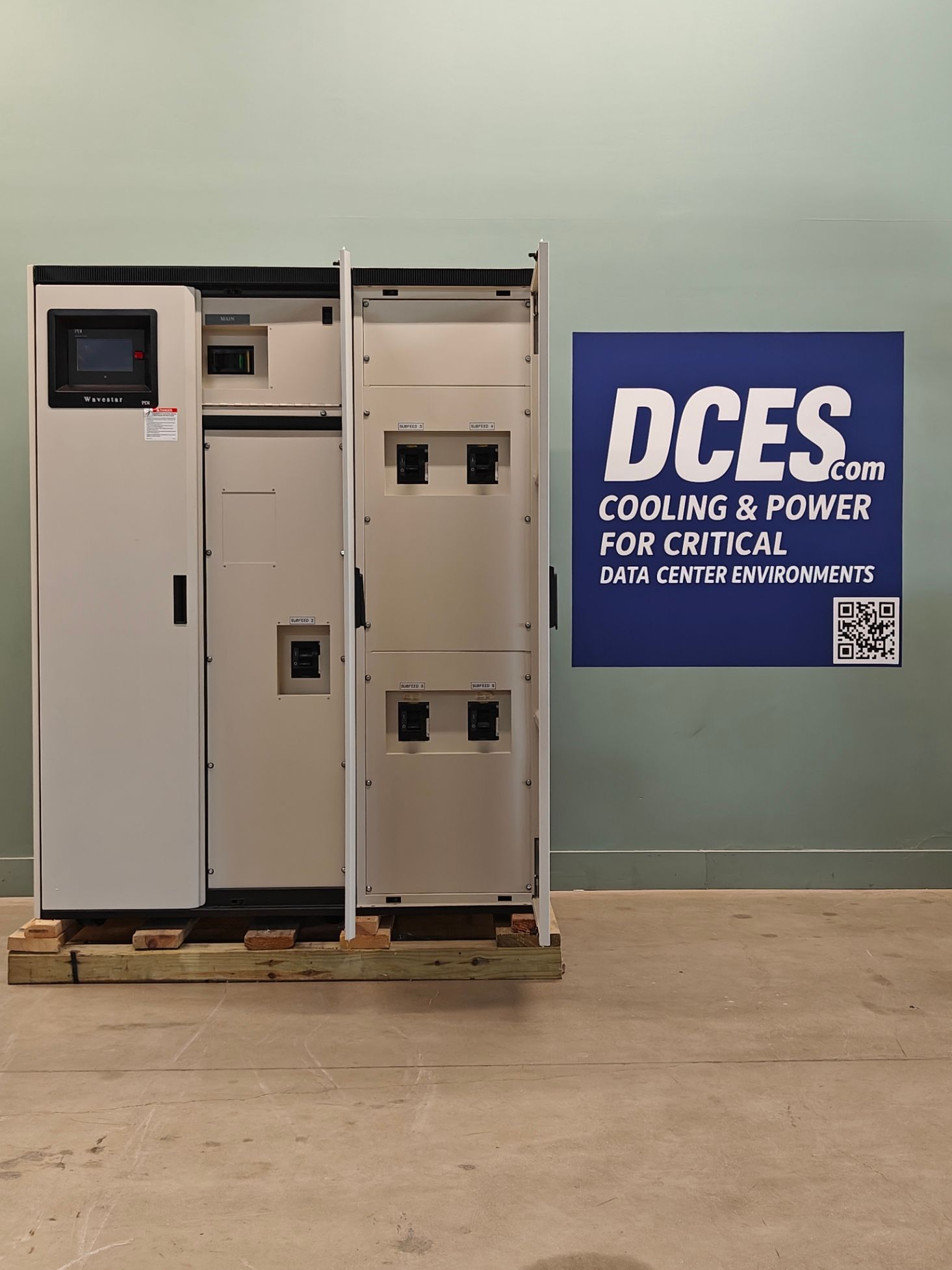 Electrical cabinet with open doors on a wooden pallet, near a blue sign reading 