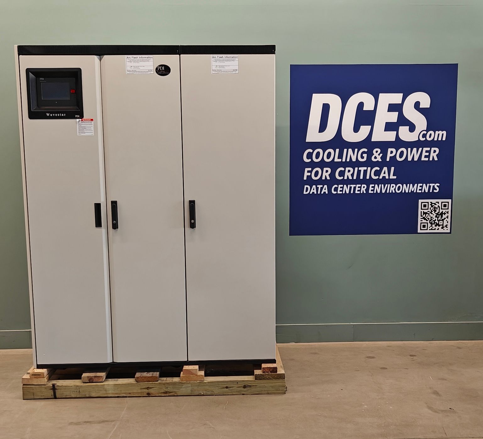 Gray cabinet with monitor, on a wooden pallet, next to a blue DCES sign.