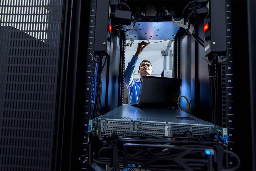 A man is working on a server in a data center.