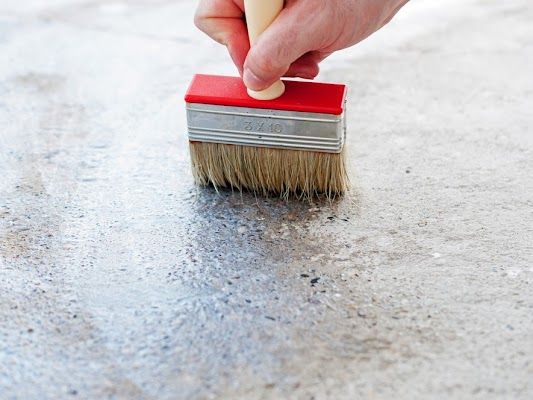 A Person Is Using A Brush To Paint A Concrete Surface — River2Coast Concreting in Boambee, NSW