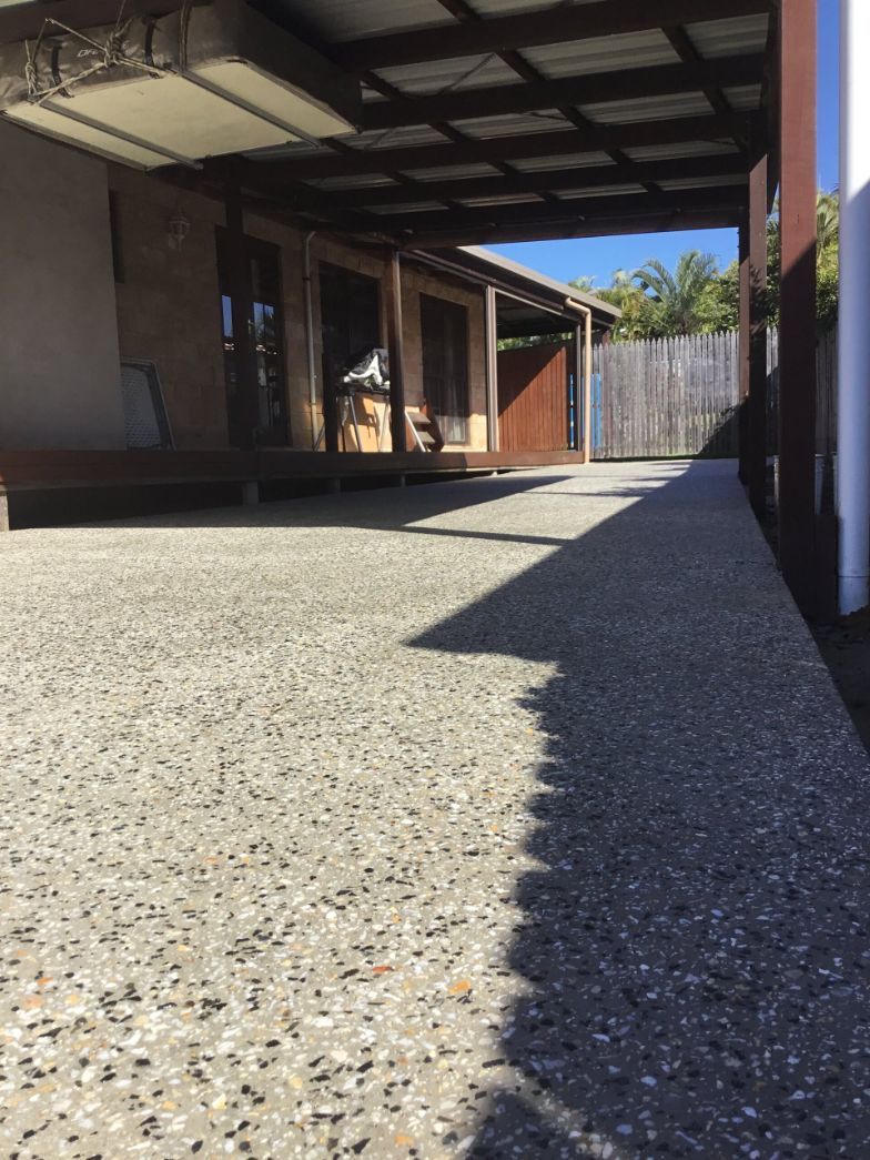 A Concrete Driveway Leading To A House With A Carport  — River2Coast Concreting in Boambee, NSW