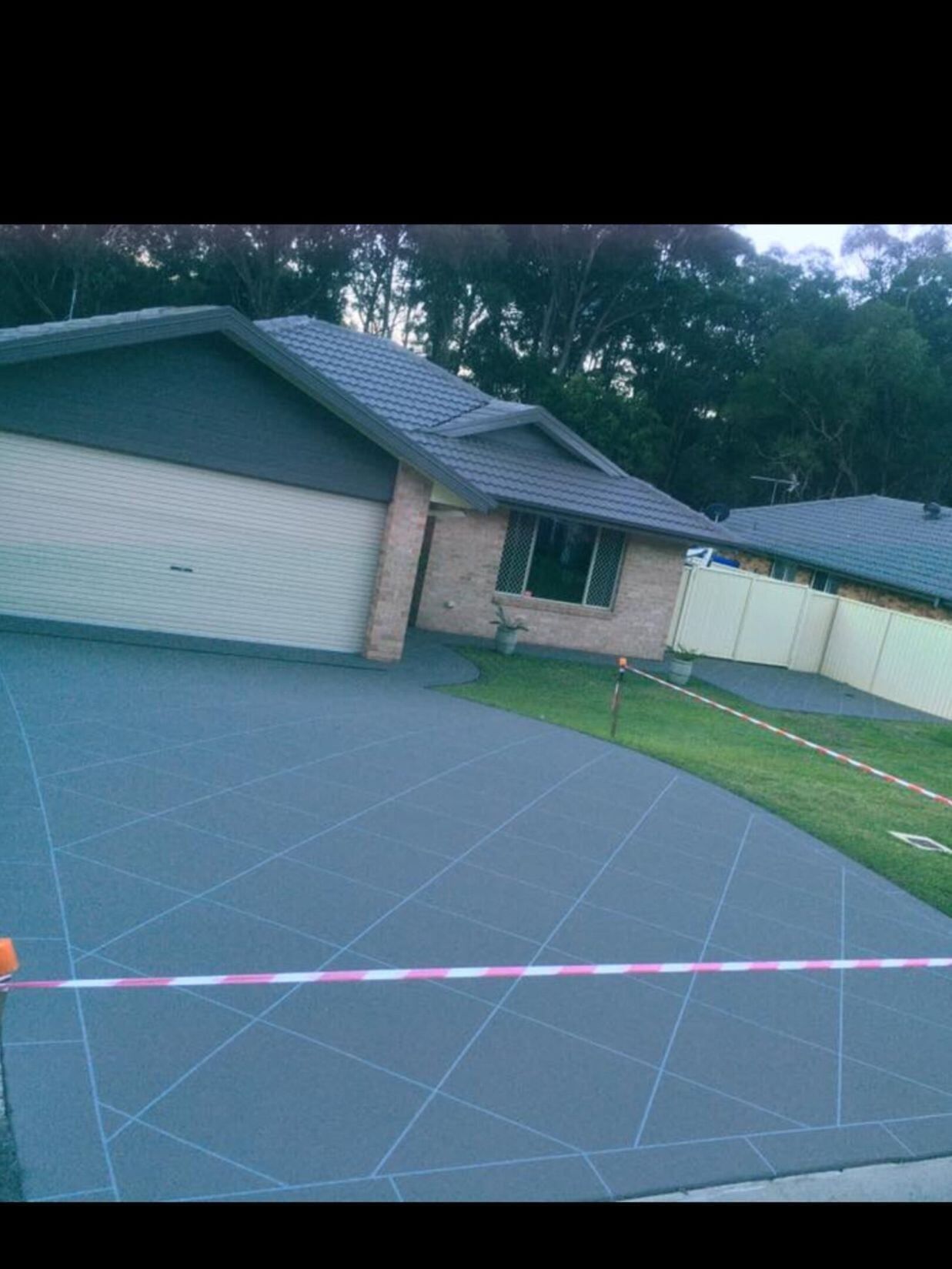 A Driveway Leading To A House With A Fence And Trees In The Background  — River2Coast Concreting in Coffs Harbour, NSW