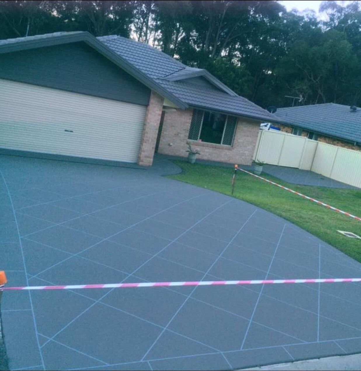 A Driveway Leading To A House With A Fence And Trees In The Background  — River2Coast Concreting in Boambee, NSW