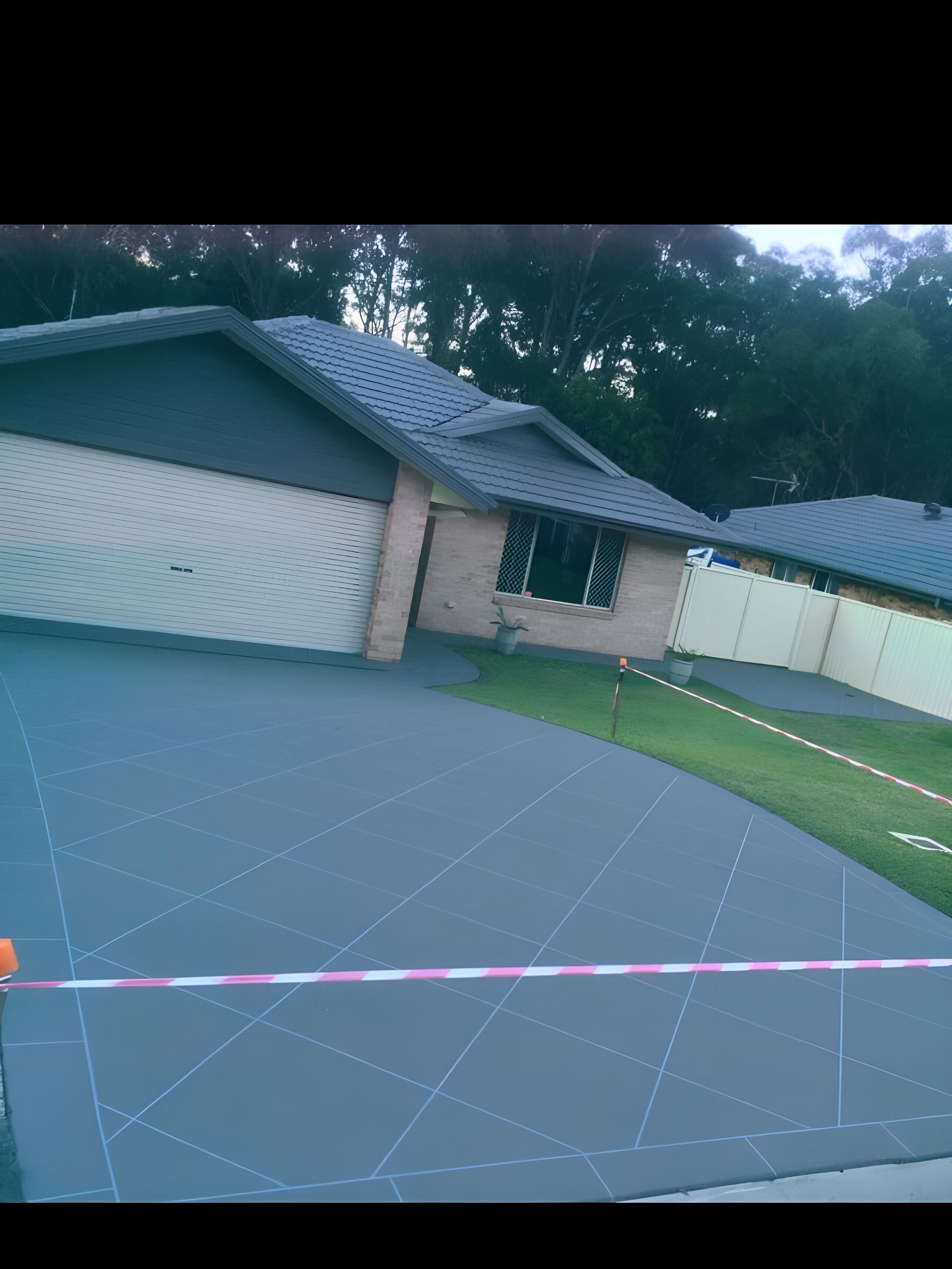 A House With A Garage And A Driveway In Front Of It  — River2Coast Concreting in Boambee, NSW