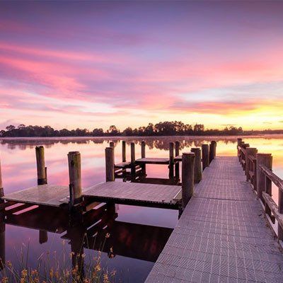 A Dock Overlooking A Lake With A Sunset In The Background  — River2Coast Concreting in Boambee, NSW