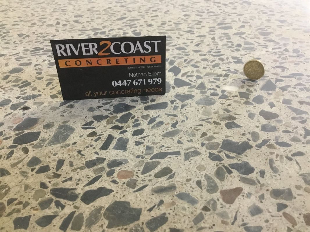 A River Coast Concrete Sign Is Sitting On A Concrete Floor — River2Coast Concreting in Boambee, NSW