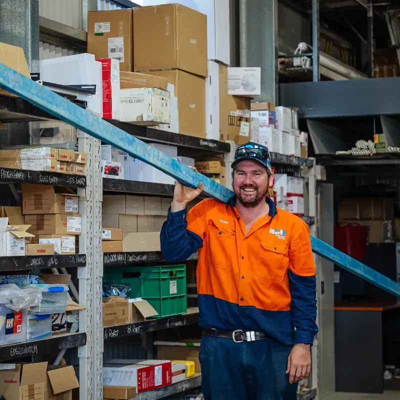 A man is holding a large piece of metal in a warehouse.