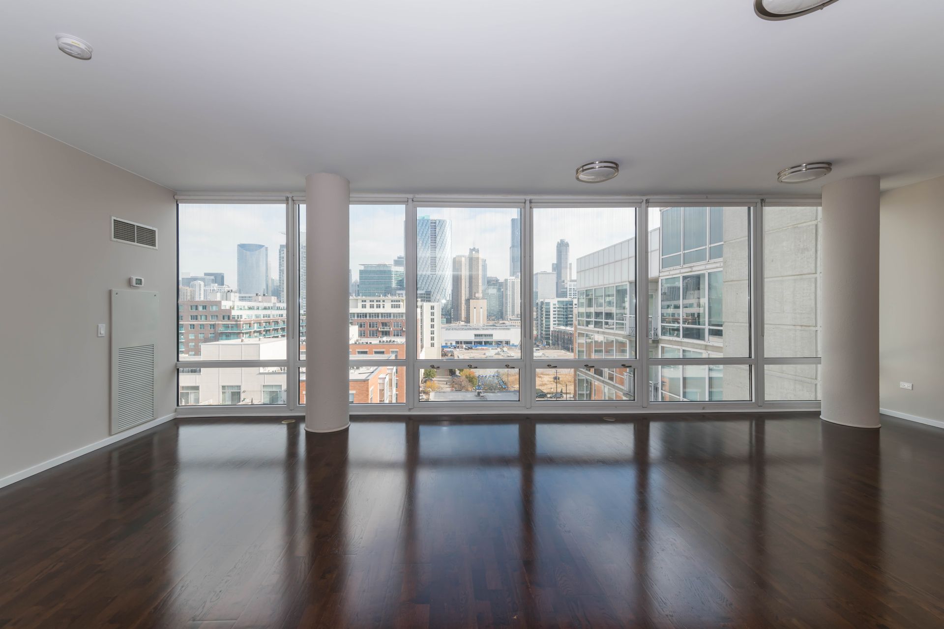 A large empty room with a view of a city at 24 S Morgan Apartments.