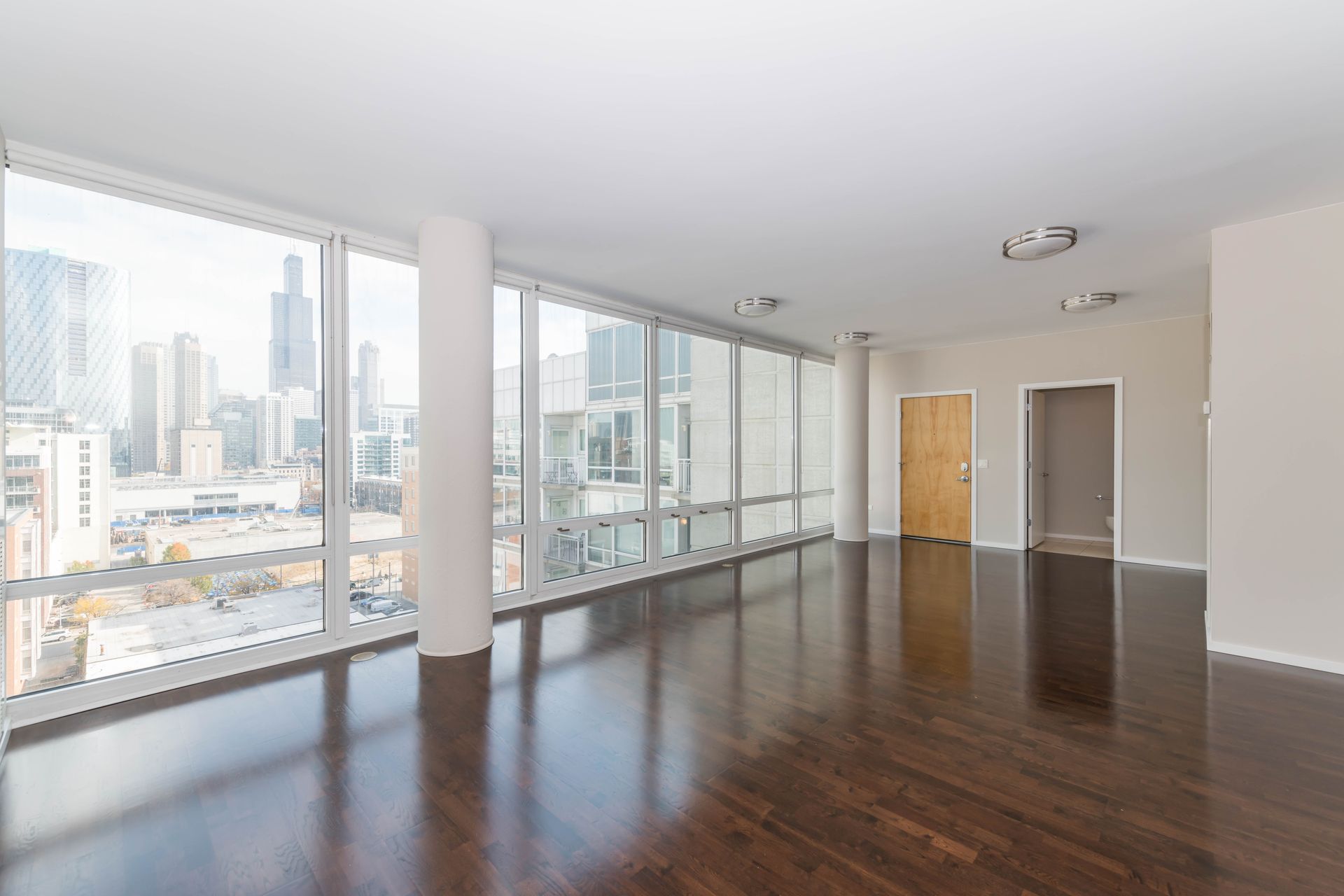 An empty apartment with a lot of windows and hardwood floors at 24 S Morgan Apartments.