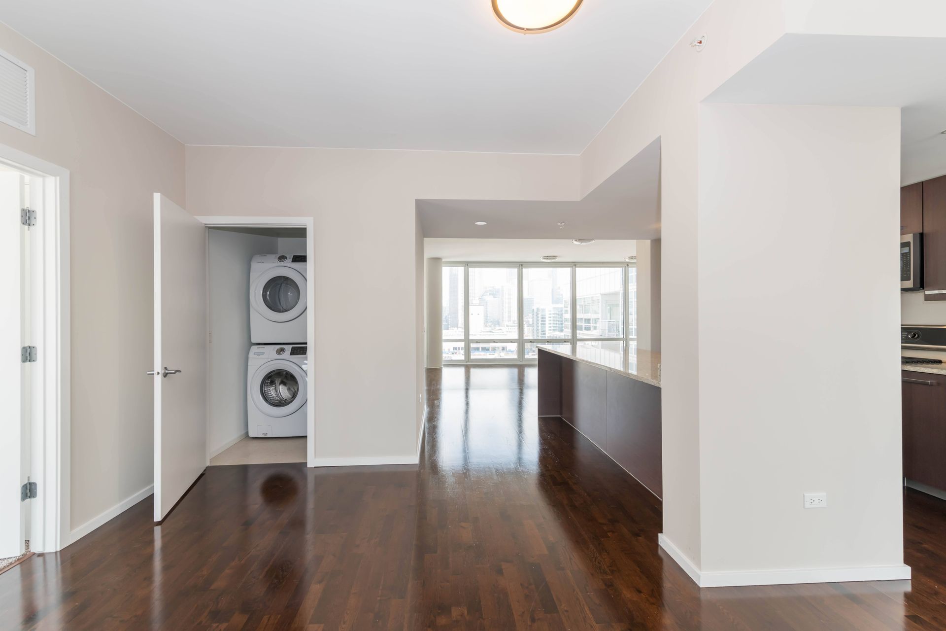 an empty living room with a washer and dryer in it and a kitchen