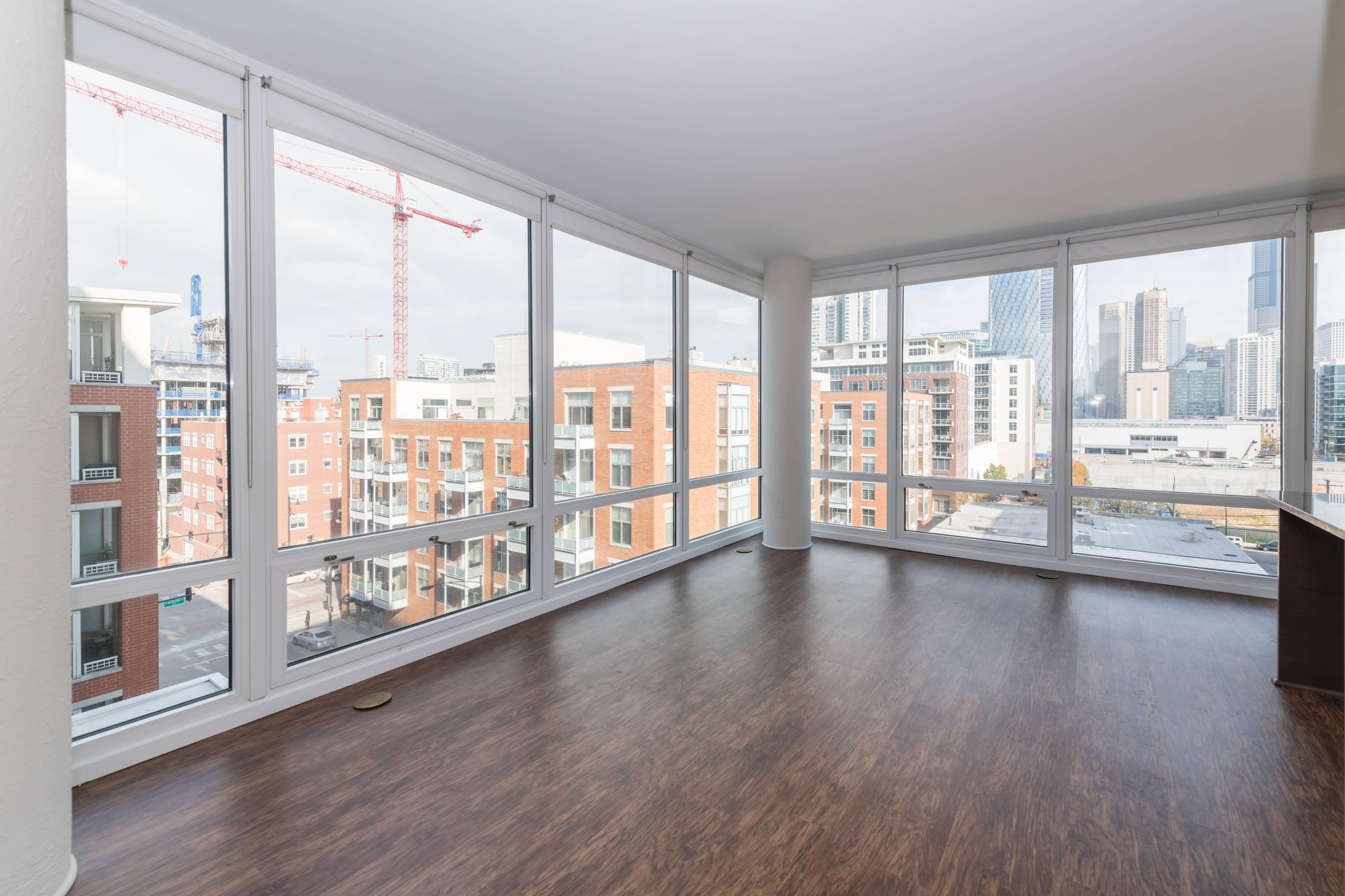 the living room of an apartment with wood floors and large windows