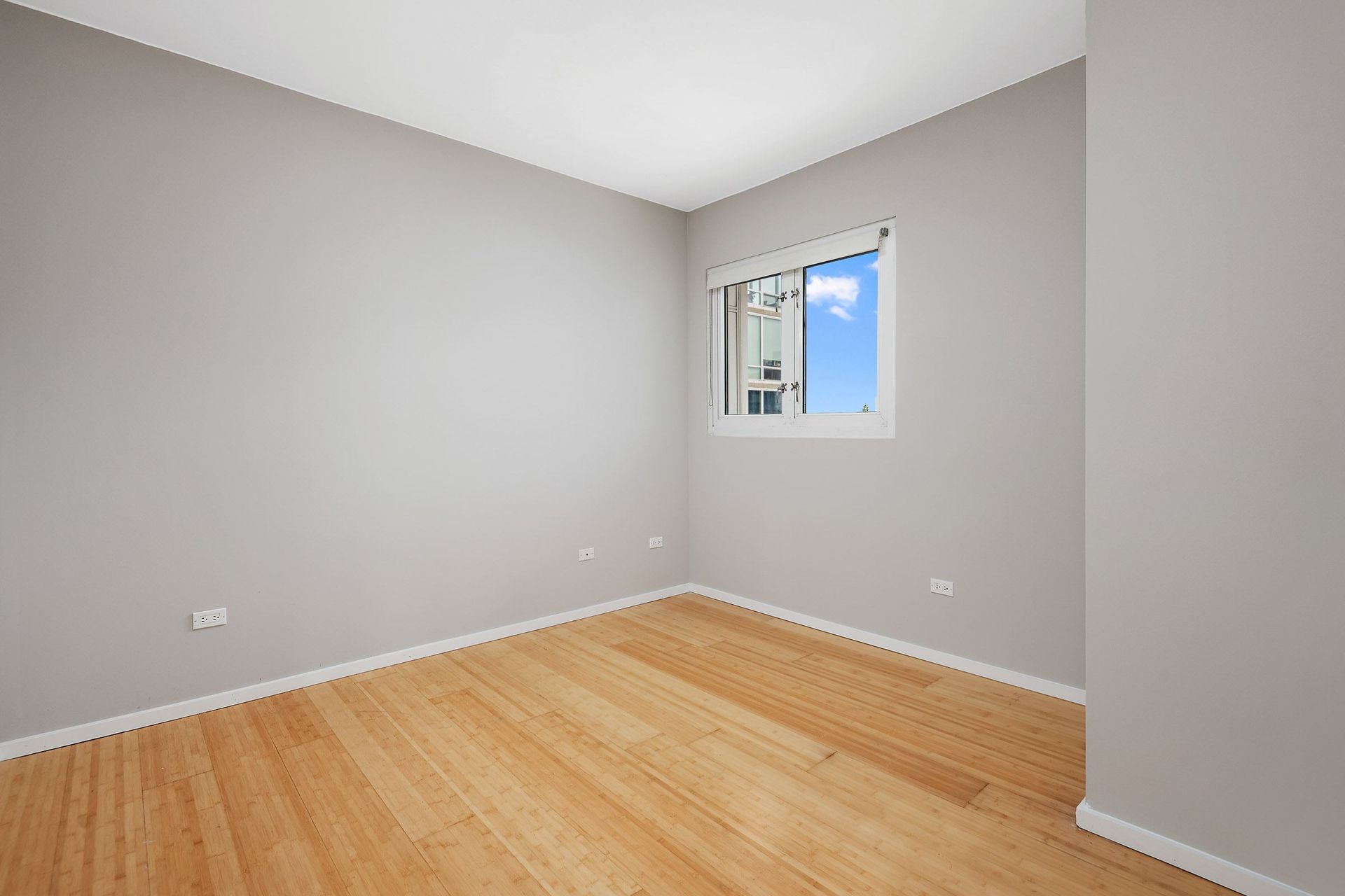 a bedroom with grey walls and a wooden floor