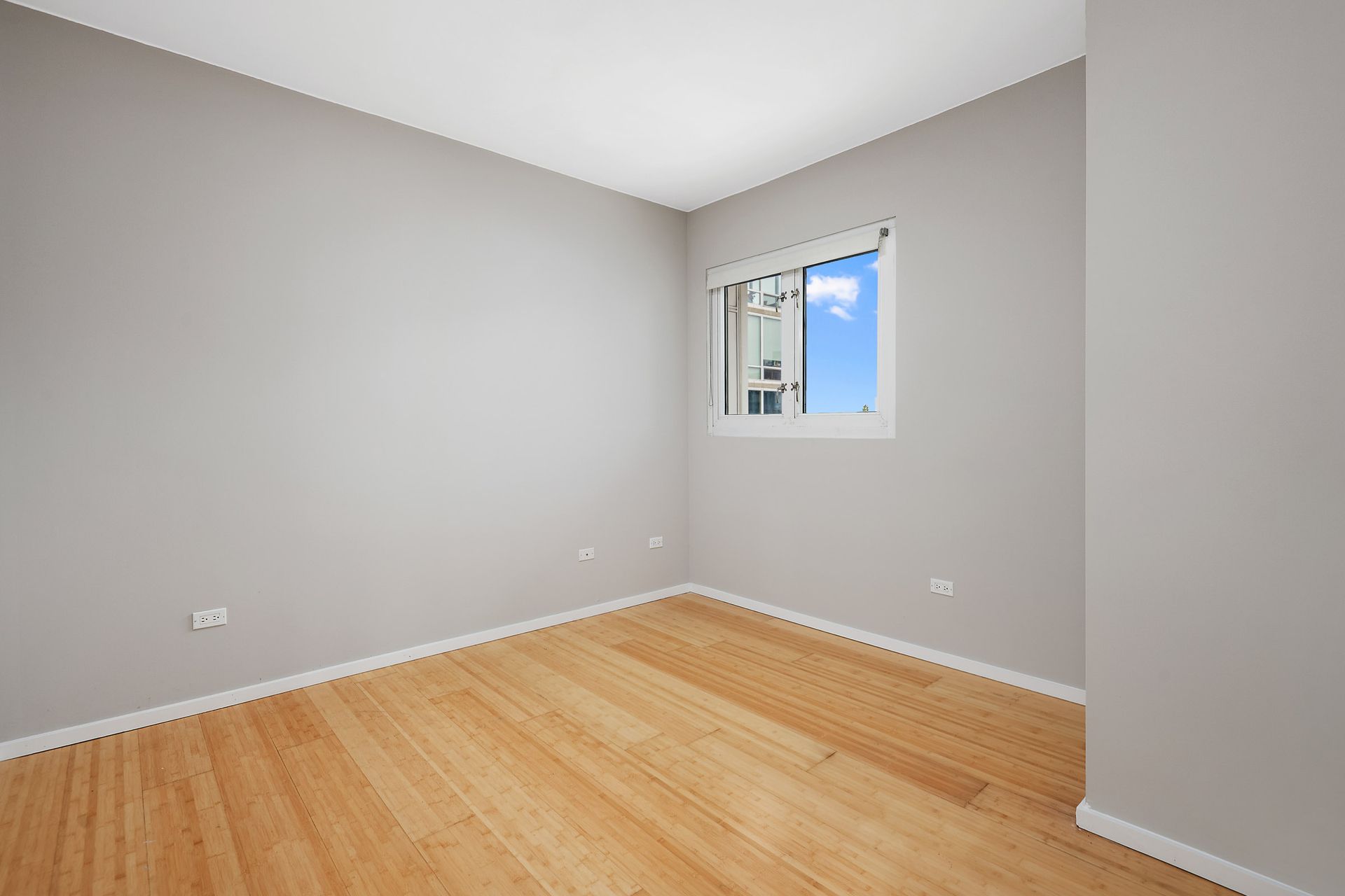 An empty room with hardwood floors and a window at 24 S Morgan Apartments.