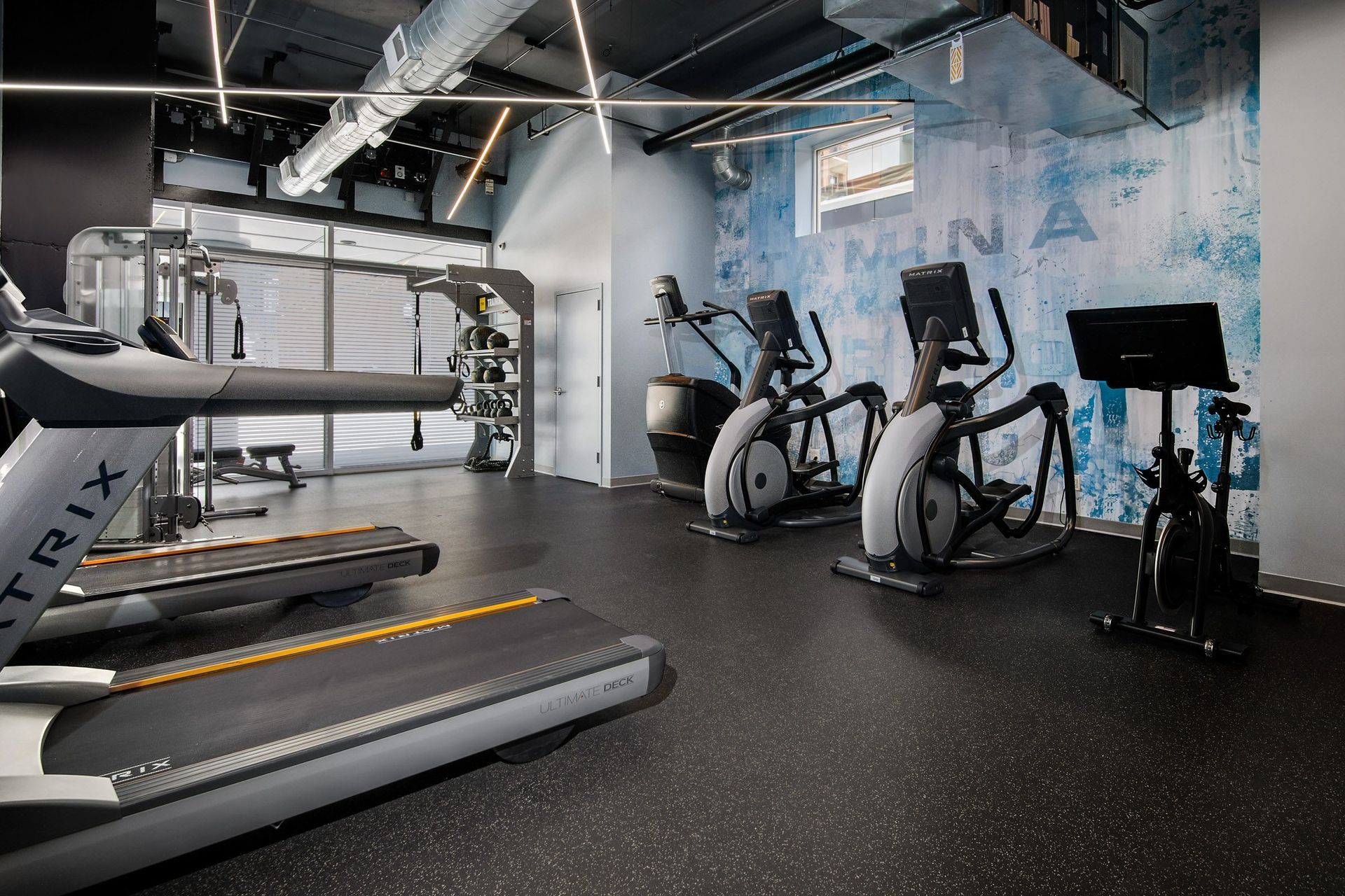 a gym with treadmills and other exercise equipment in a building with blue walls