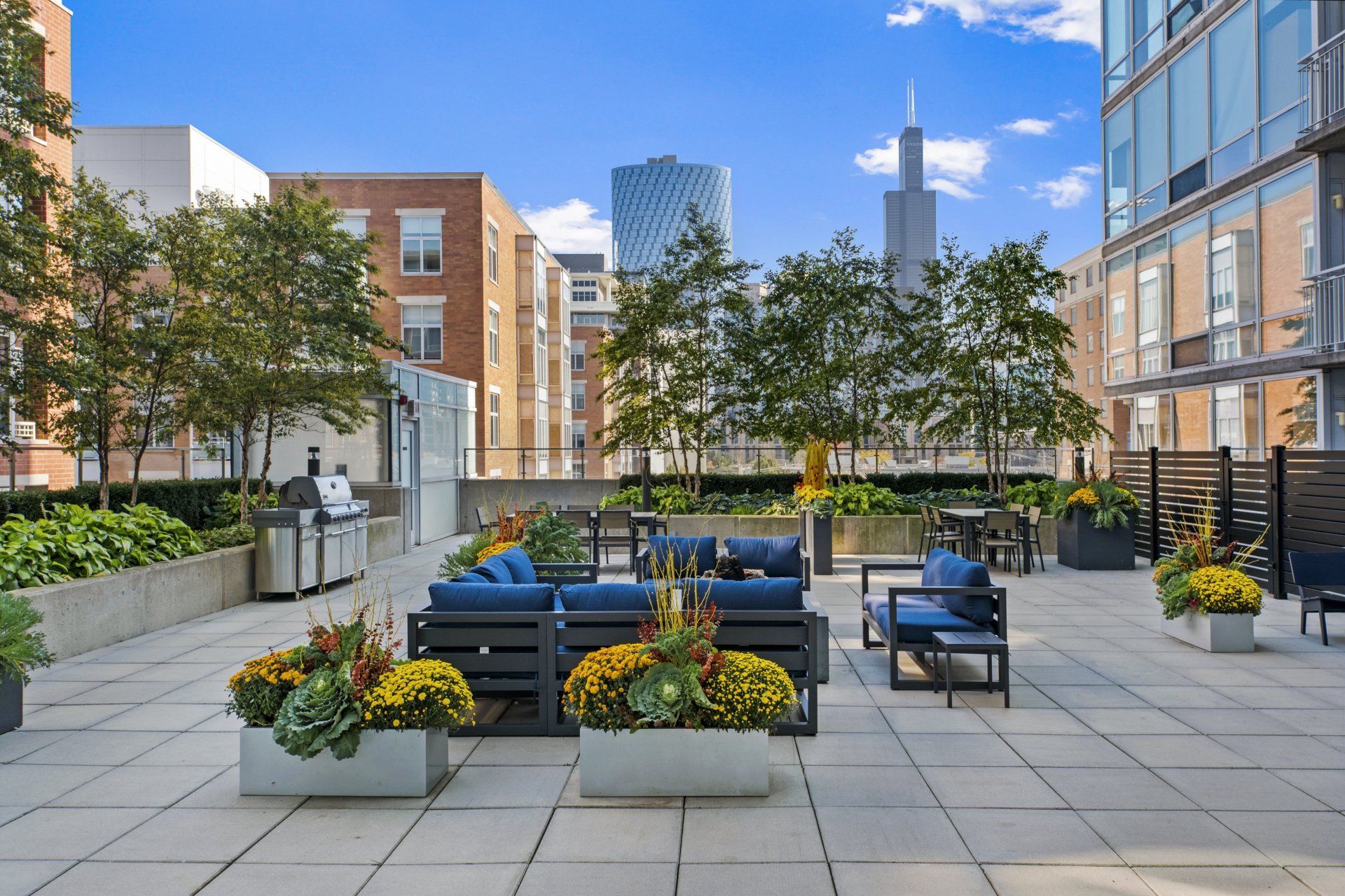 A patio with furniture and flowers in front of a building at 24 S Morgan Apartments.