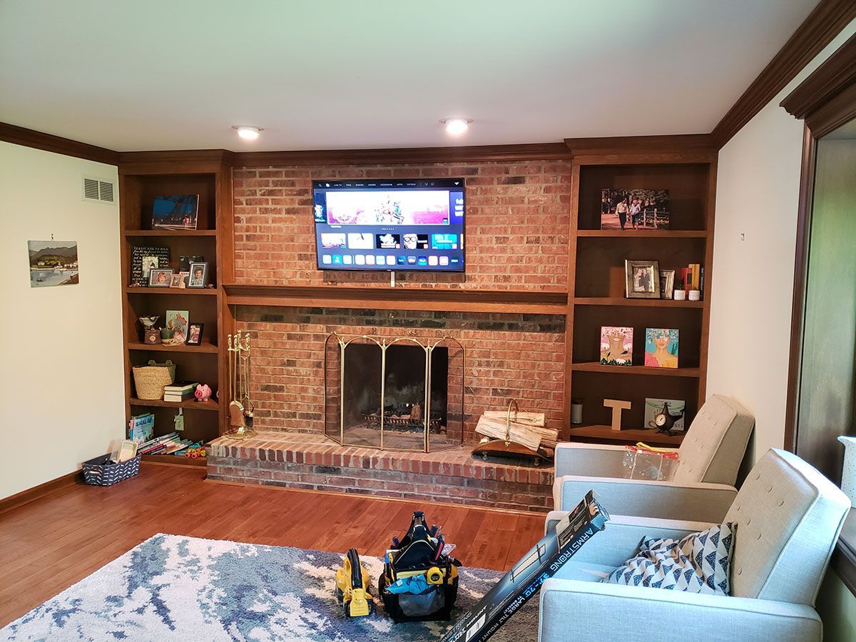 A living room with a fireplace and a flat screen tv on the wall.