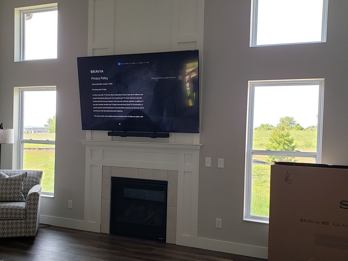 A living room with a fireplace and a flat screen tv on the wall.