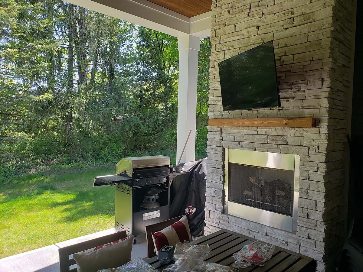 A patio with a fireplace and a flat screen tv.