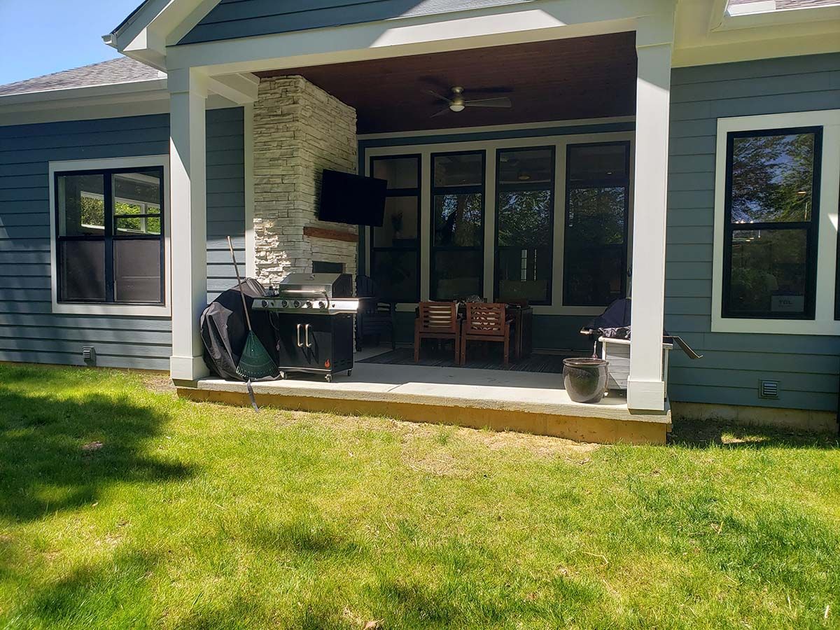 A house with a porch and a grill in the backyard.