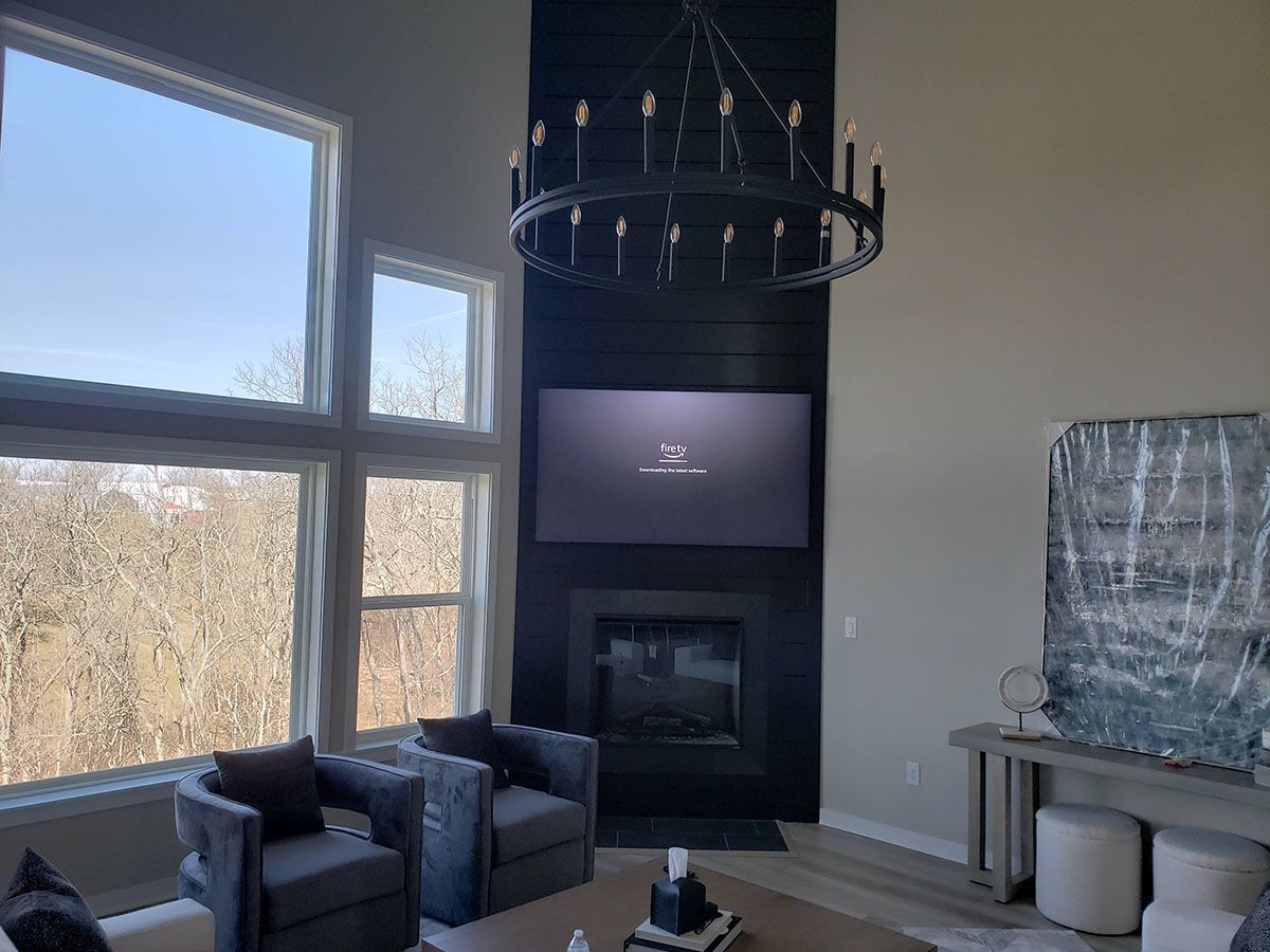 A living room with a fireplace , chairs , a television and a chandelier.