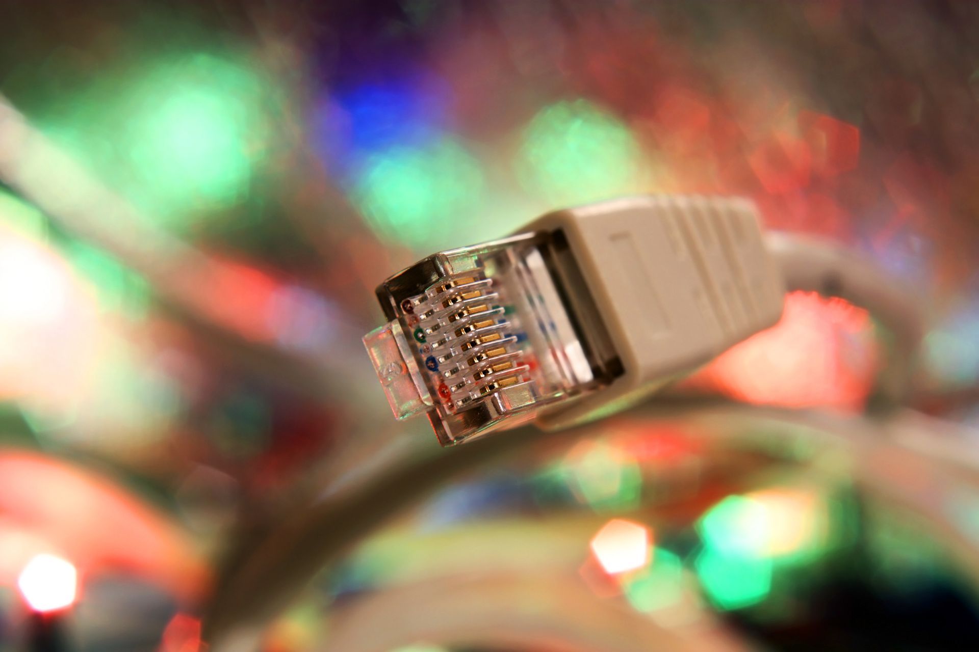 A close up of an ethernet cable with christmas lights in the background.