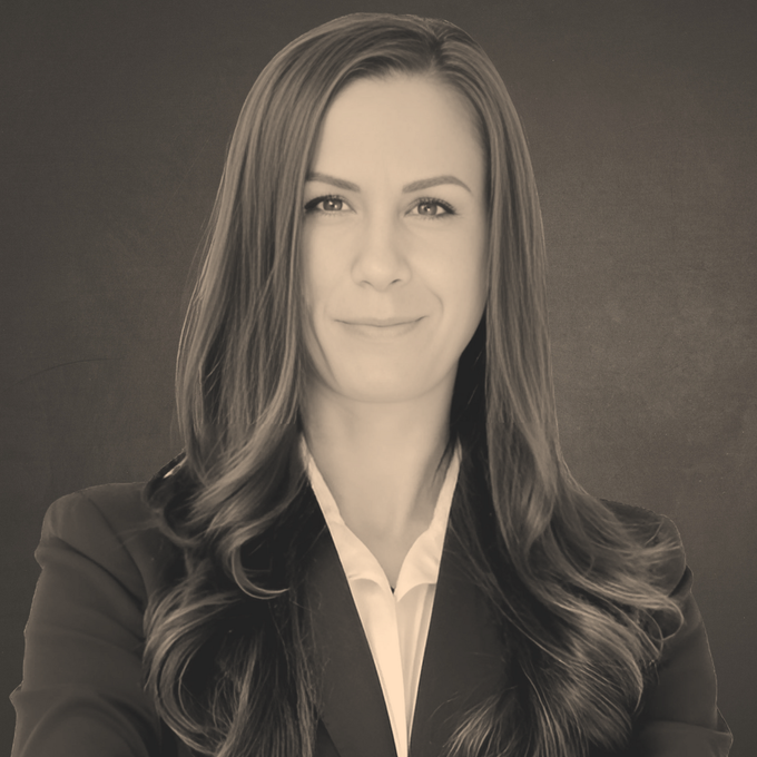 Alyssa Barry: A woman with long hair is wearing a suit and smiling