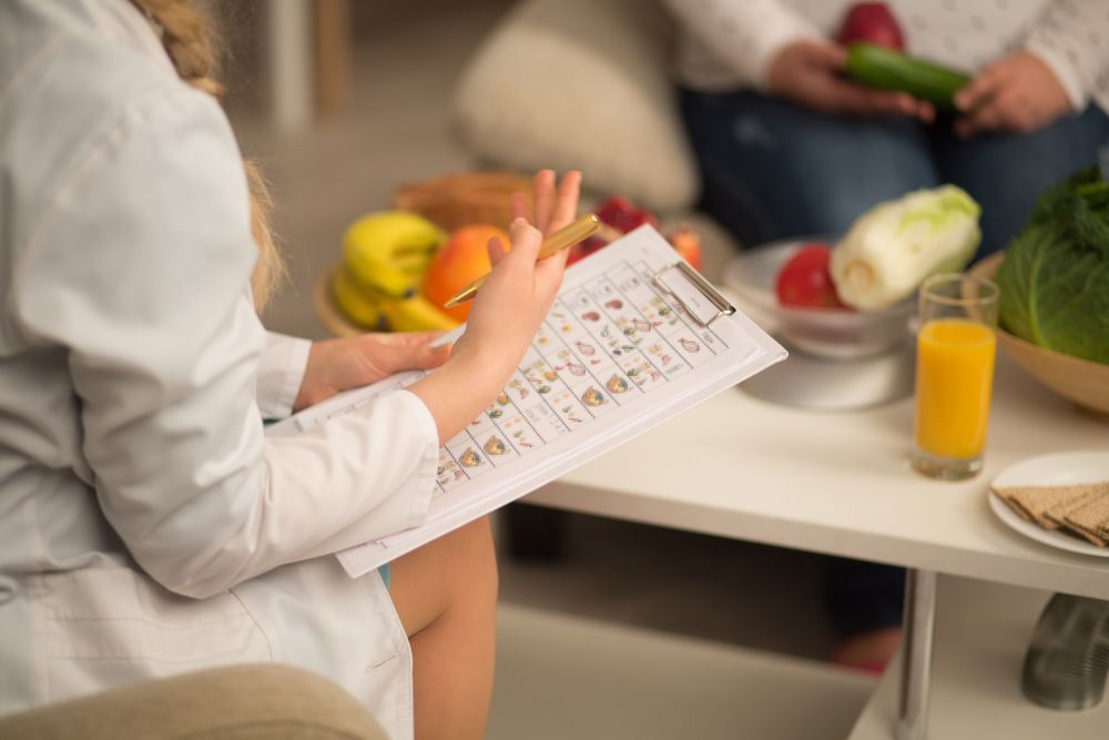 Person Filling Out a Form at a Table With Fruit — HealthPoint Mingara In Tumbi Umbi, NSW