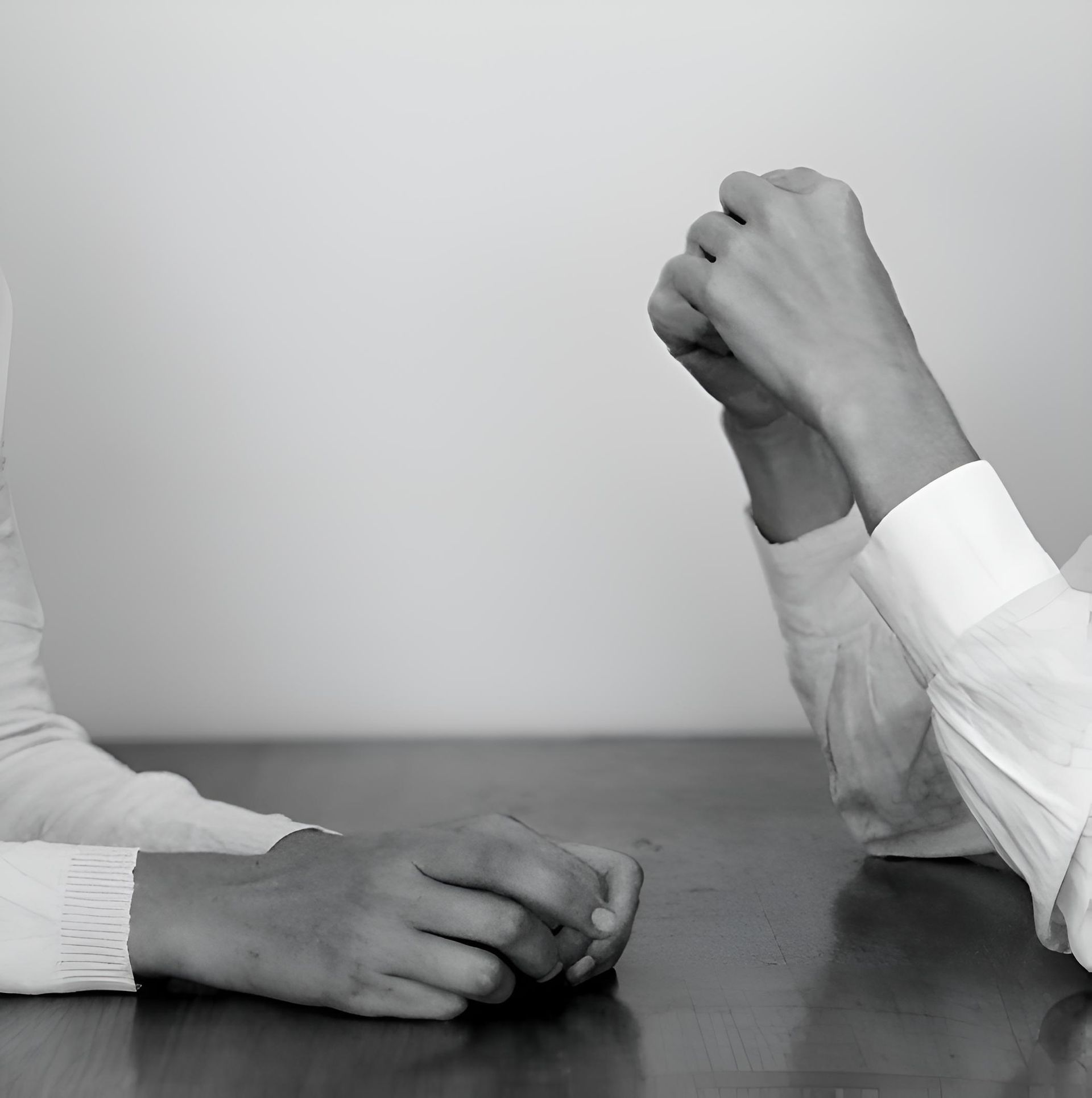 Two people are sitting at a table with their hands folded — HealthPoint Mingara In Tumbi Umbi, NSW