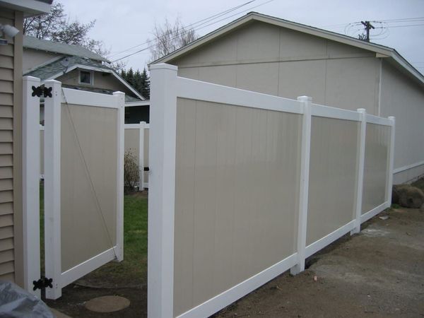 Tan and white vinyl fence with gate; outdoors near beige house.