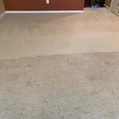A man is cleaning a couch with a vacuum cleaner.