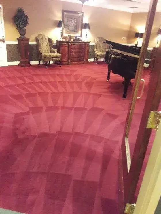 A living room with a red carpet and a piano.