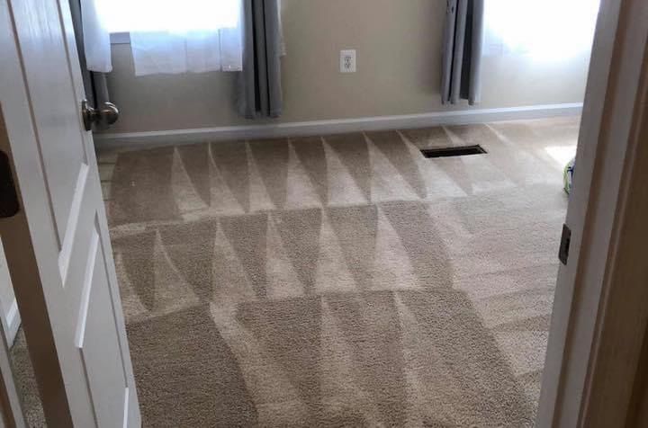 A bedroom with a carpeted floor and a window.