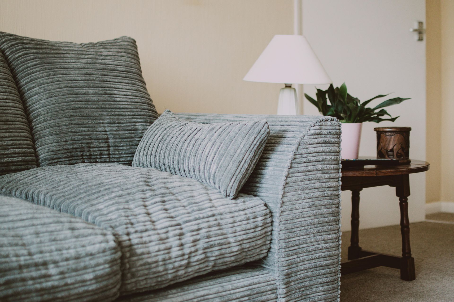 A living room with a couch , table , lamp and potted plant.