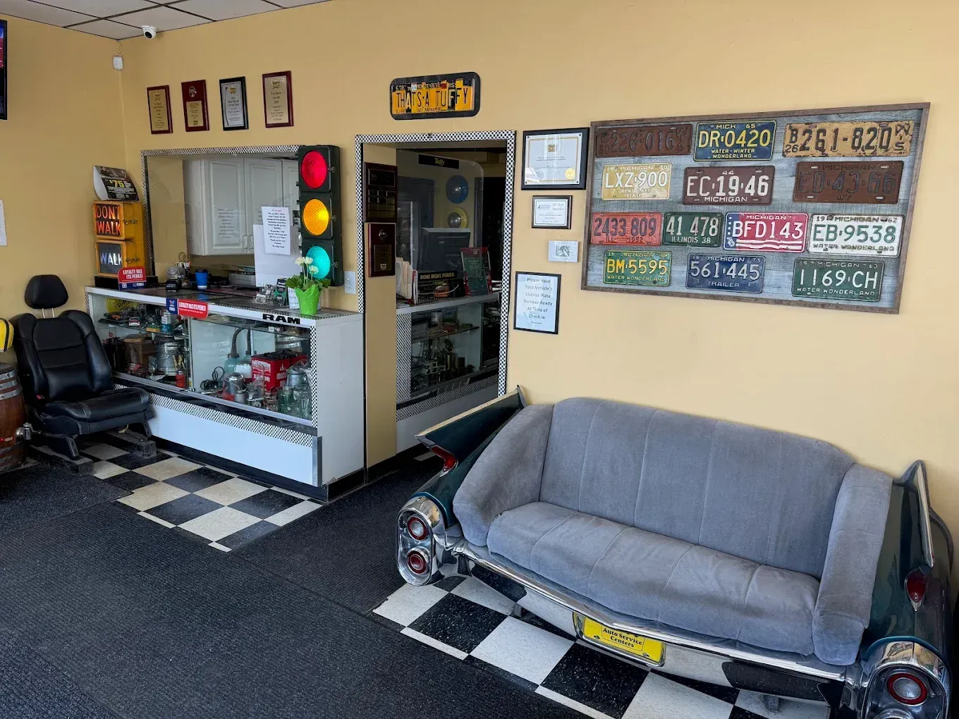 Car-themed waiting area with a couch made from a car, a black and white checkered floor, and license plate art.