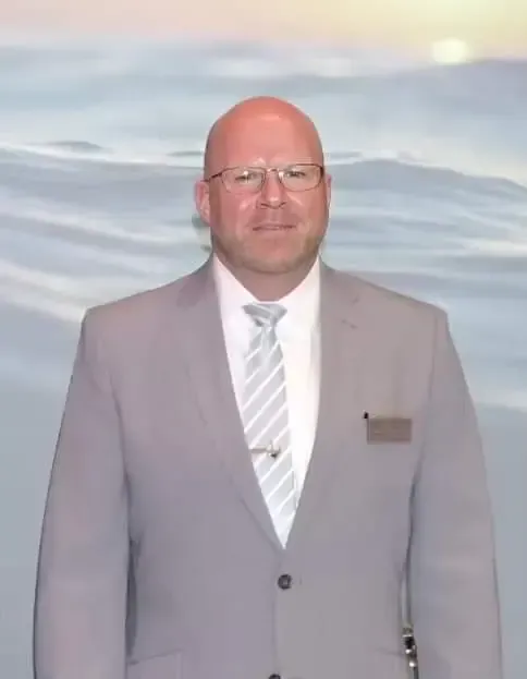 A man in a suit and tie is standing in front of a painting of the ocean.