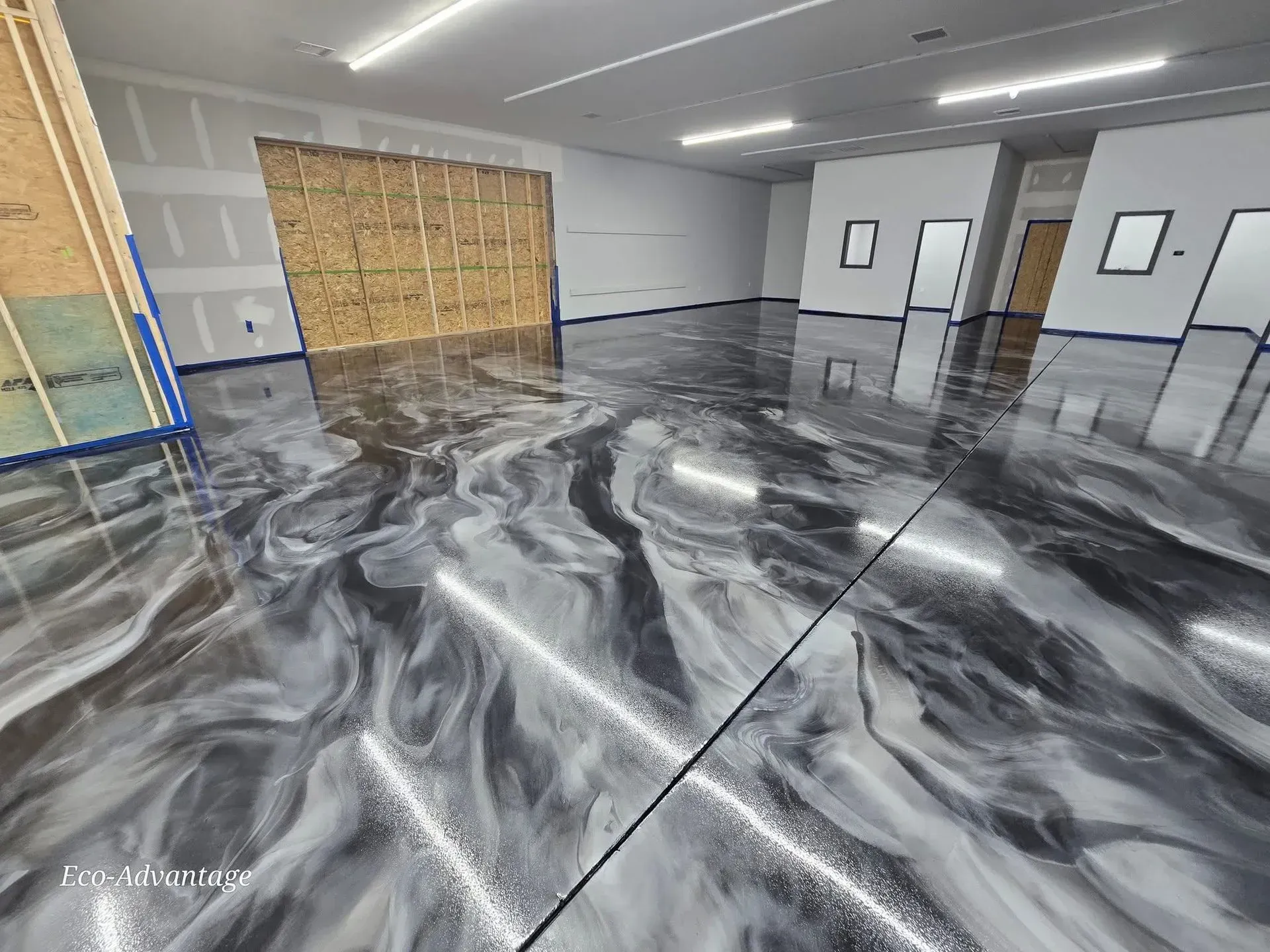 Empty room with glossy black-and-white marbled floor, white walls, and a few windows and doors.