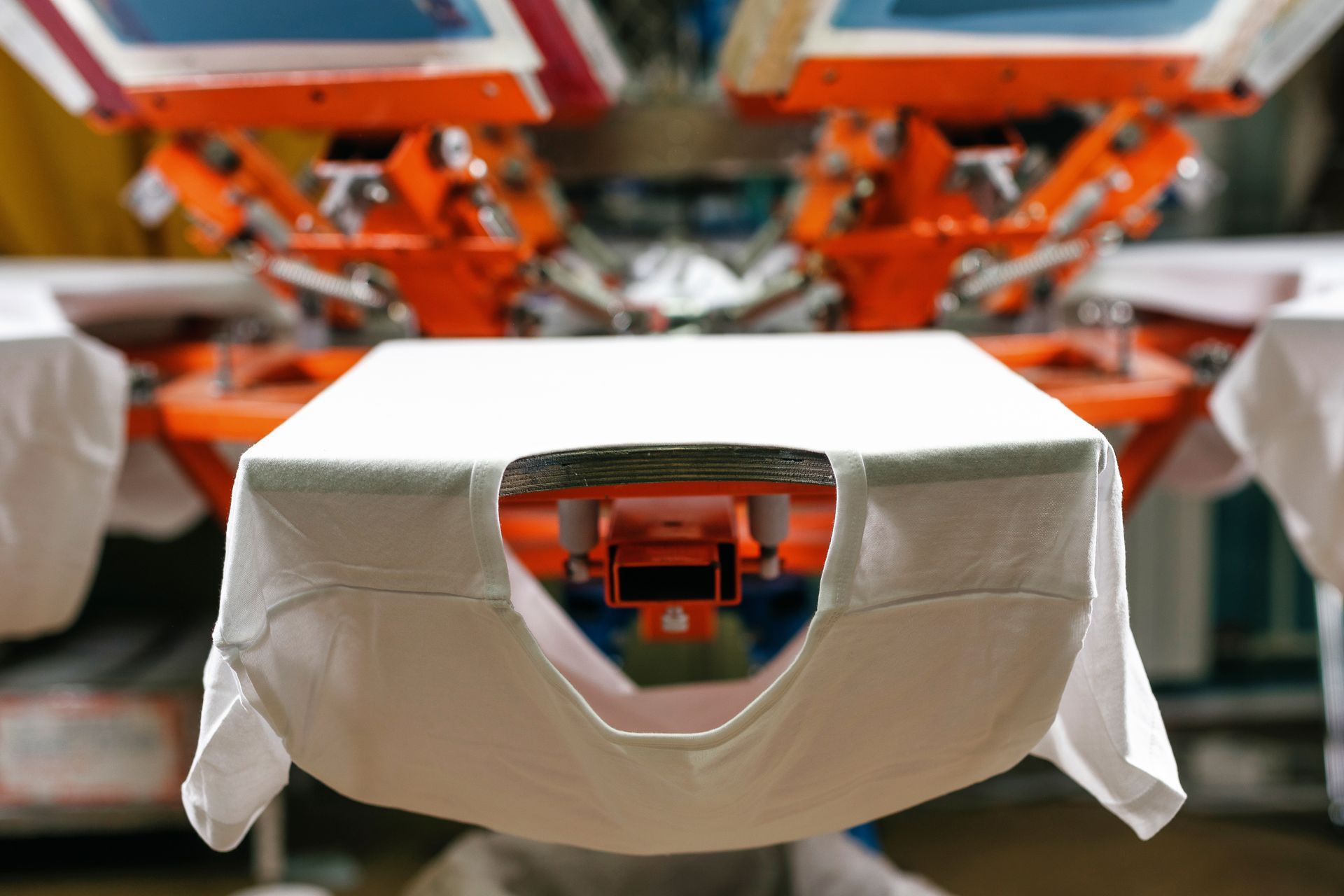 A blank white T-shirt stretched on a screen-printing press ready for custom design application.