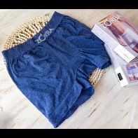 Unos pantalones cortos azules de Zorba sobre una estera de mimbre junto a una caja de ropa interior de Zorba.