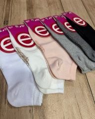 Seis pares de calcetines tobilleros en blanco, crudo, rosa, gris y negro, sobre una superficie de madera.