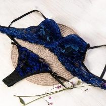 Conjunto de lencería de encaje azul: sujetador y tanga sobre una base tejida, delicados detalles florales.