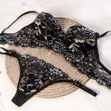 Conjunto de lencería de encaje azul: sujetador y tanga sobre una base tejida, delicados detalles florales.