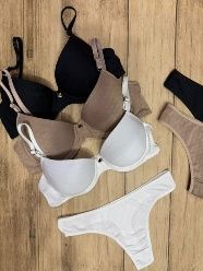 Sujetadores y ropa interior en varios colores neutros dispuestos sobre una superficie de madera.