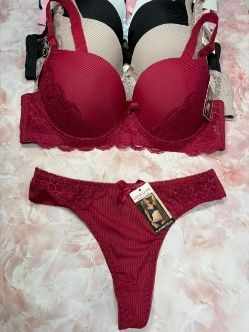 Conjunto de lencería roja, sujetador y tanga, con otros sujetadores al fondo.