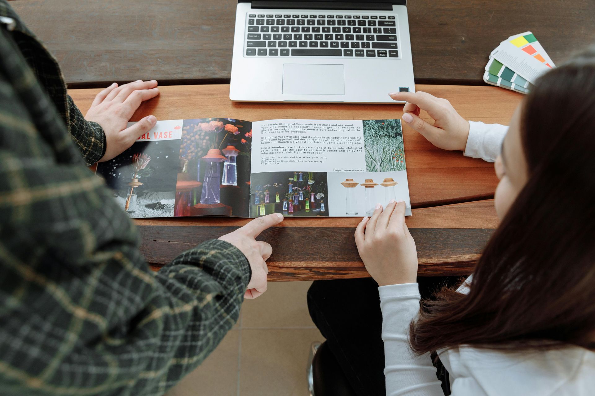 A man and a woman are sitting at a table looking at a brochure.
